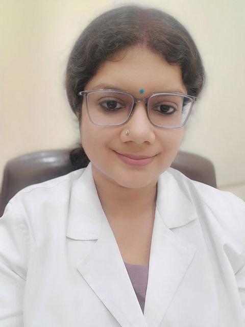 Dr. Neha Kumari in a white coat and glasses
